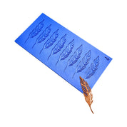 Blue silicone mat with eight feather-shaped tuile molds and a finished golden feather.