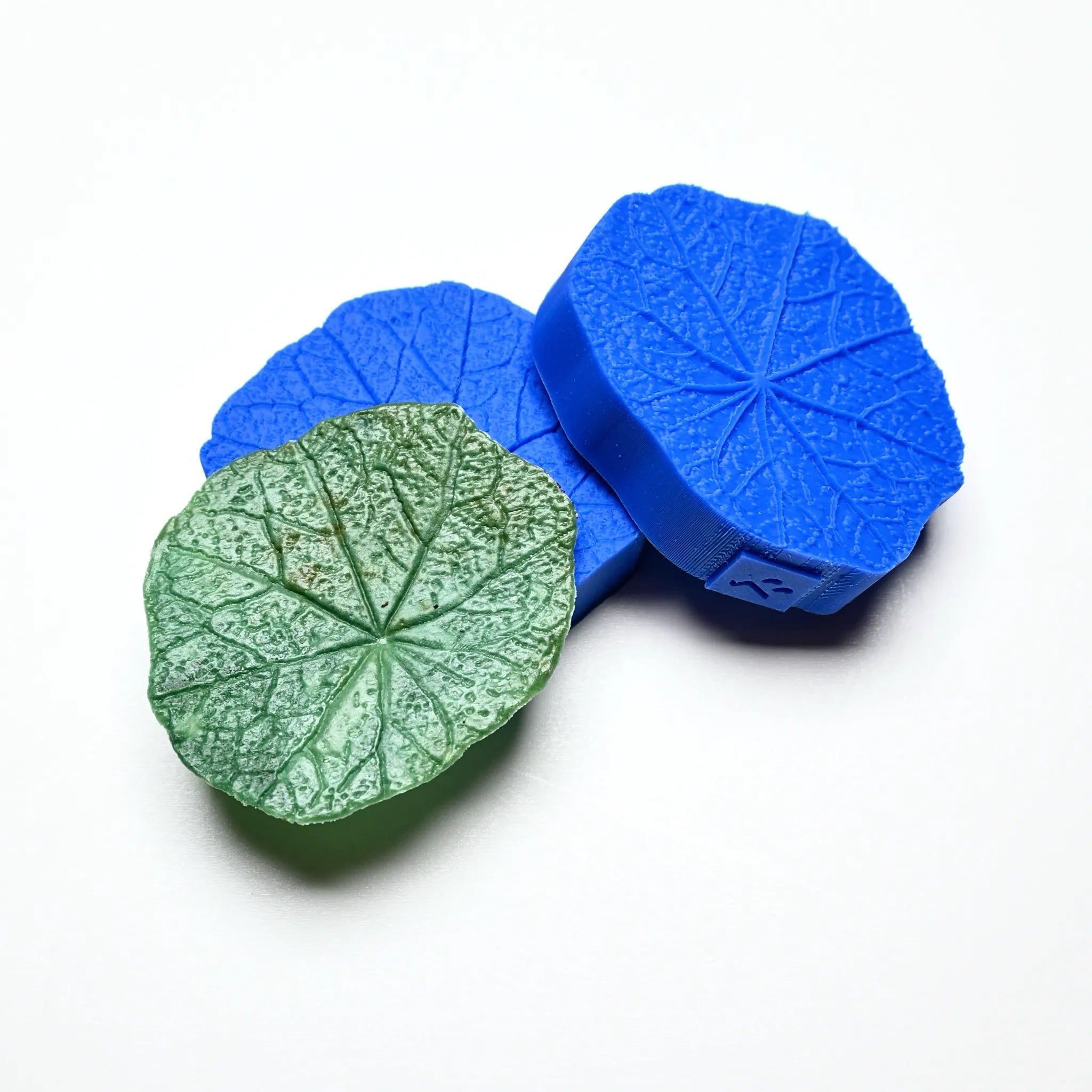 Round blue silicone nasturtium leaf molds with a textured green leaf replica.