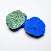 Round blue silicone nasturtium leaf press mold with a textured green leaf replica.
