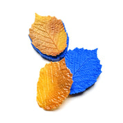 Blue silicone hazelnut leaf molds with detailed vein textures and realistic pastry leaves.