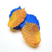 Blue hazelnut leaf silicone pastry molds with realistic brown textured edible leaves.
