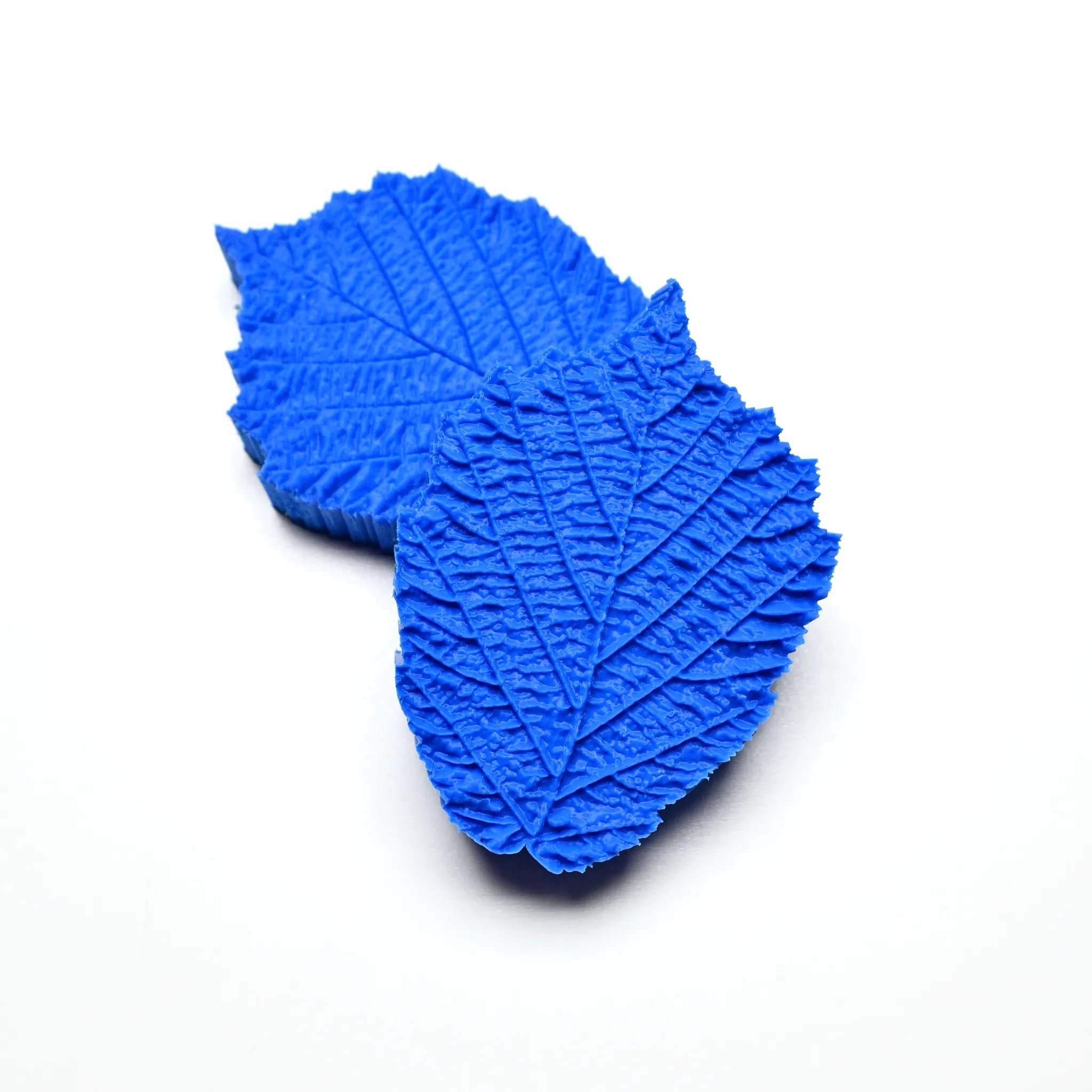 Two blue silicone hazelnut leaf molds showing detailed vein textures on a white background.