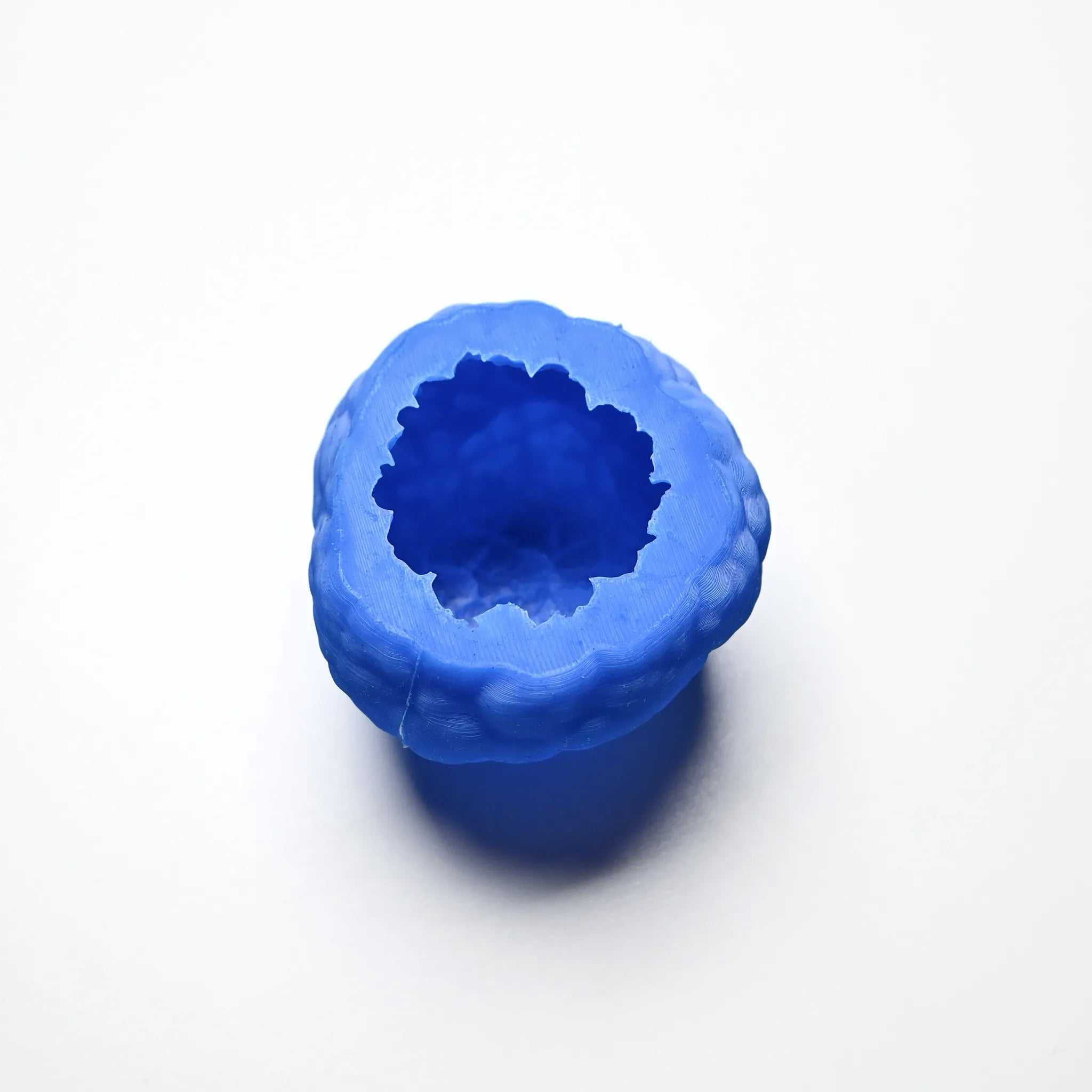Blue textured silicone truffle mold with a hollow, irregular round shape on a white background.