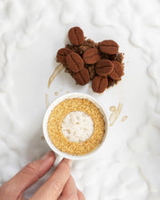 Brown textured coffee bean-shaped desserts made with a mini silicone mold next to an espresso cup.