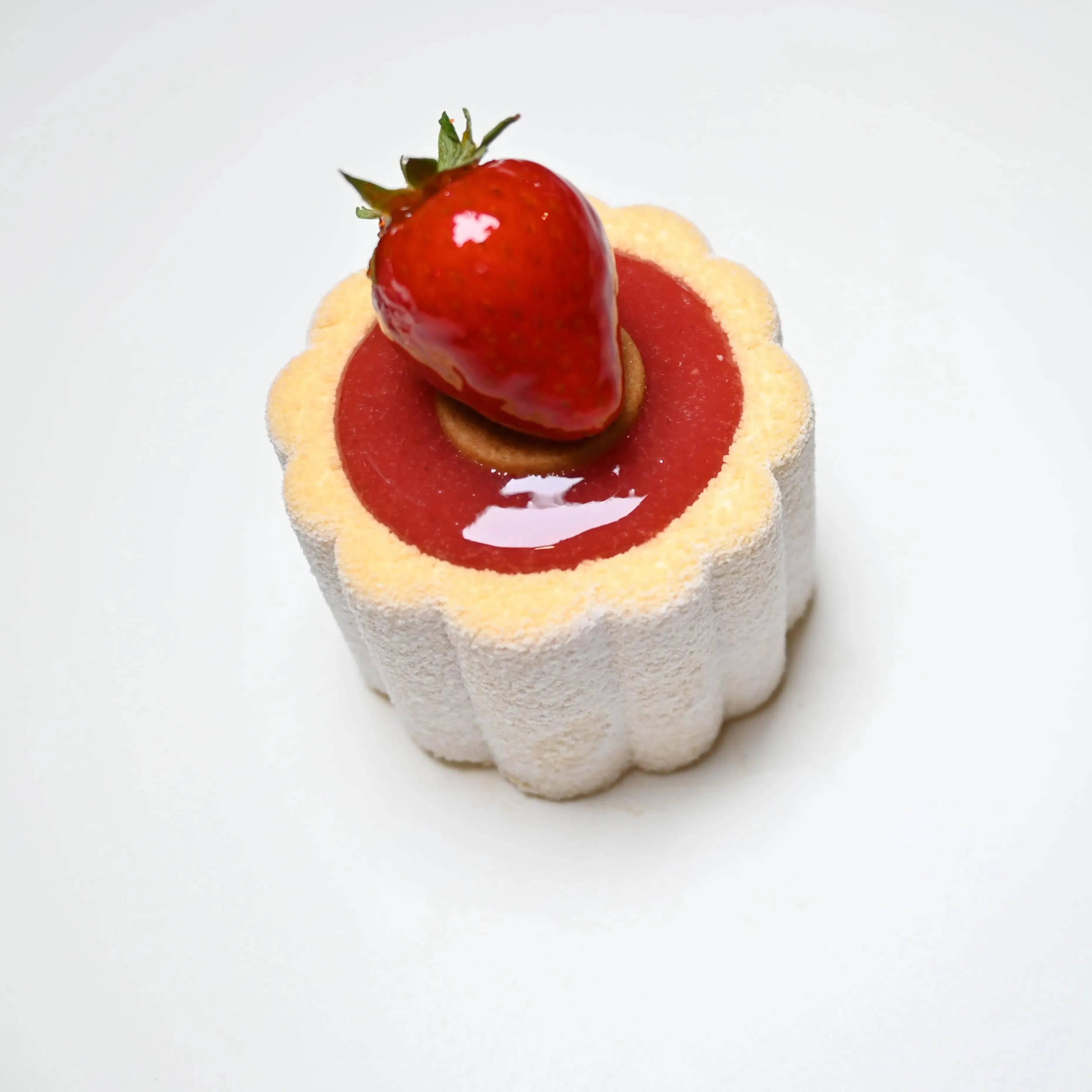 Mini Charlotte dessert with fluted sides, red glaze, and a fresh strawberry on top.